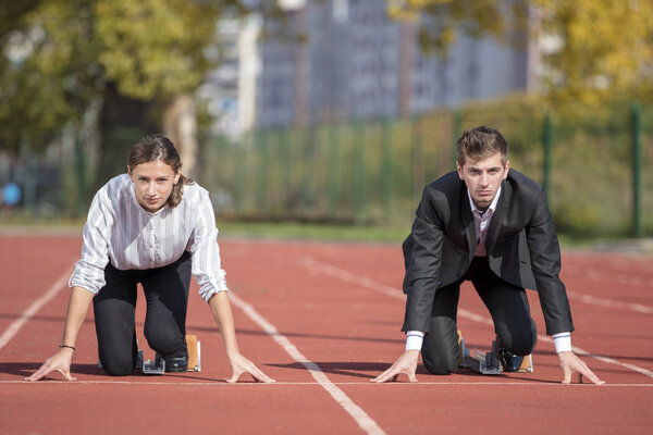 Close up of 20 year old businessmen and businesswoman ready to run at start point.