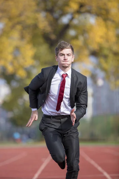 Joven hombre de negocios en traje corriendo en la pista — Foto de Stock