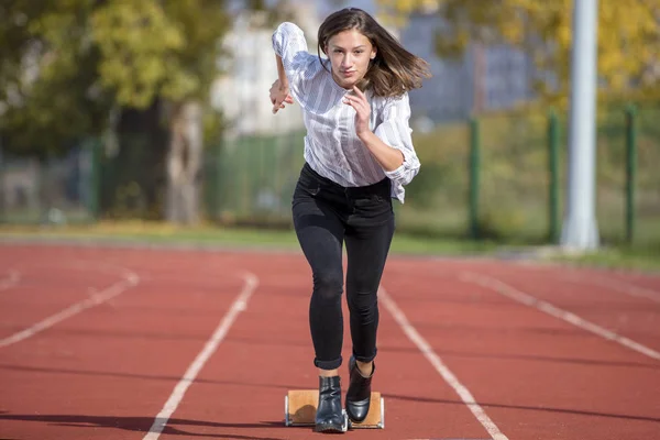 Mujer de negocios en posición de inicio lista para correr y correr en pista de atletismo —  Fotos de Stock