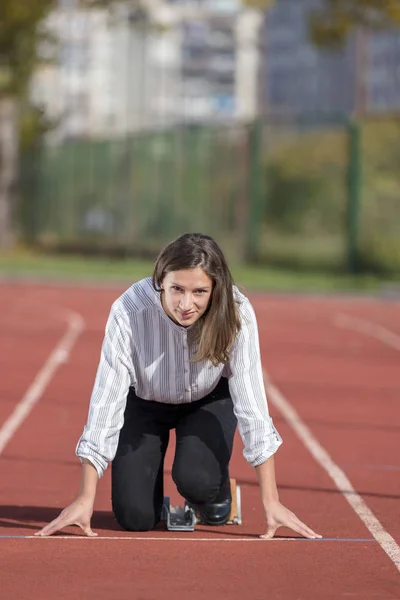 Mujer de negocios en posición de inicio lista para correr y correr en pista de atletismo —  Fotos de Stock