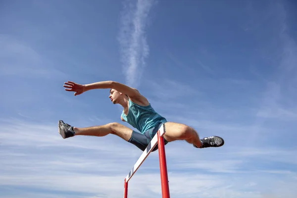Low angle view of determined male athlete jumping over a hurdles — Stock Photo, Image