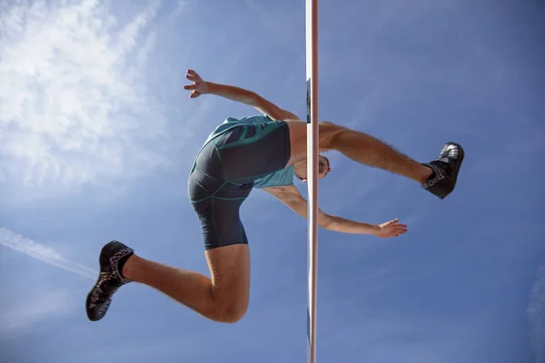 Vista de ángulo bajo del atleta masculino determinado que salta sobre un obstáculo — Foto de Stock