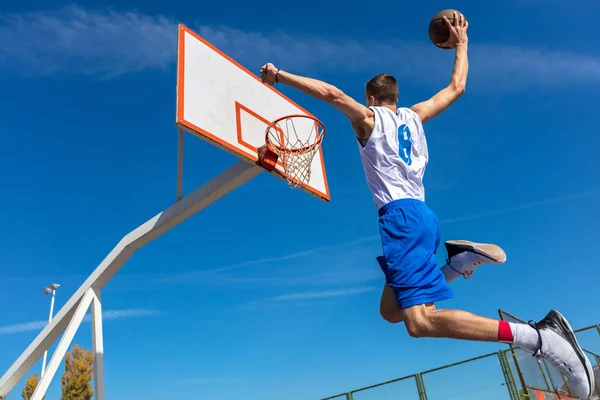 Jovem jogador de basquete de rua fazendo slam dunk — Fotografia de Stock