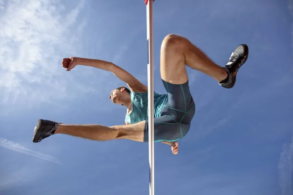Vista de ángulo bajo del atleta masculino determinado que salta sobre un obstáculo — Foto de Stock