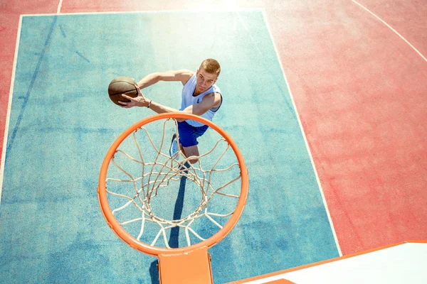 Joven saltando y haciendo un fantástico slam dunk jugando streetball, baloncesto. Auténtico urbano. — Foto de Stock