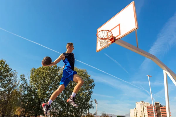 Jovem jogador de basquete de rua fazendo slam dunk — Fotografia de Stock