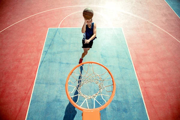 Joven saltando y haciendo un fantástico slam dunk jugando streetball, baloncesto. Auténtico urbano. — Foto de Stock