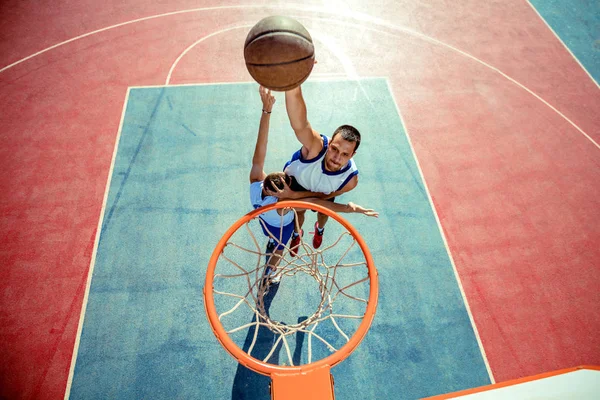 Vista de alto ângulo do jogador de basquete mascando basquete em aro — Fotografia de Stock