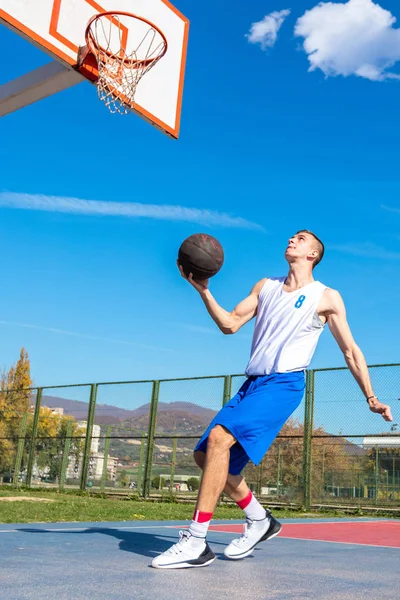 Jovem jogador de basquete de rua fazendo slam dunk — Fotografia de Stock