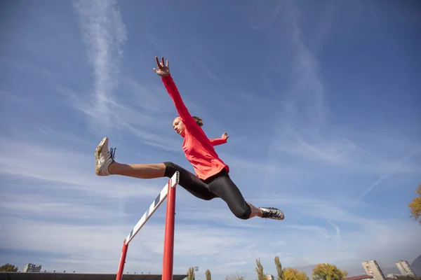 Athletin springt während des Rennens über die Hürde — Stockfoto