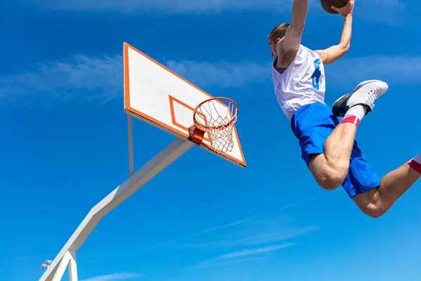 Joven jugador callejero de baloncesto haciendo slam dunk — Foto de Stock
