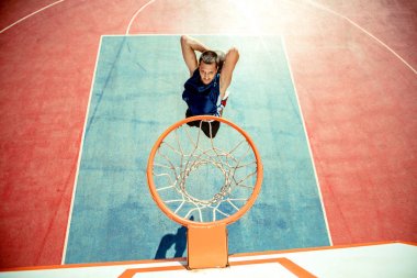 Genç adam zıplayıp smaç basıyor. Sokak basketbolu, basketbol oynuyor. Şehir otantik.