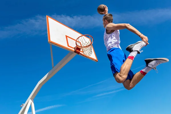 Jovem jogador de basquete de rua fazendo slam dunk — Fotografia de Stock