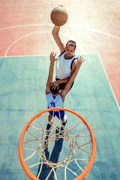 농구 선수가 엉덩이에 농구공을 박는 모습 — 스톡 사진