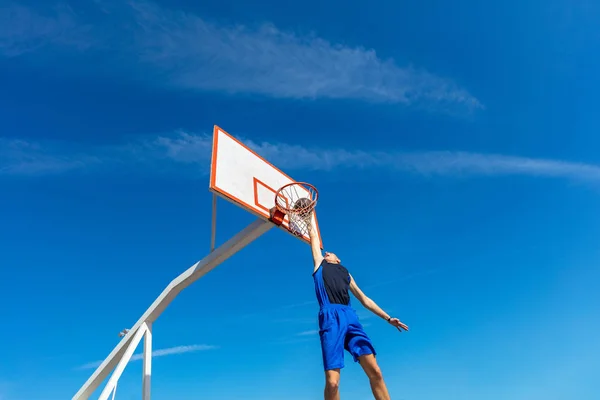 Jovem jogador de basquete de rua fazendo slam dunk — Fotografia de Stock