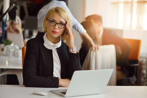 Portretul unei femei blonde partener de afaceri în 30 de ani stând la biroul ei ordonat în fața computerului ei . — Fotografie, imagine de stoc
