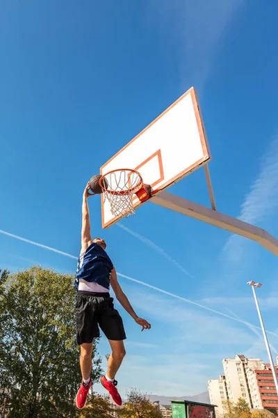 Joven jugador callejero de baloncesto haciendo slam dunk — Foto de Stock