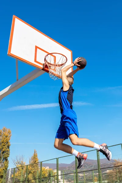 Jovem jogador de basquete de rua fazendo slam dunk — Fotografia de Stock