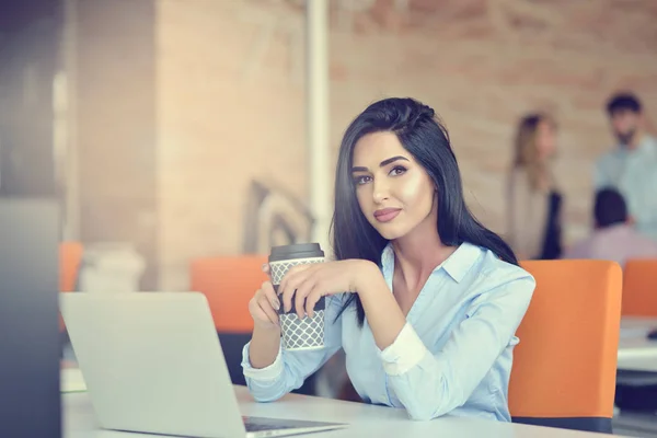 Imaginea unei femei care folosește laptopul în timp ce stă la birou . — Fotografie, imagine de stoc