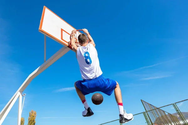 Joven jugador callejero de baloncesto haciendo slam dunk — Foto de Stock