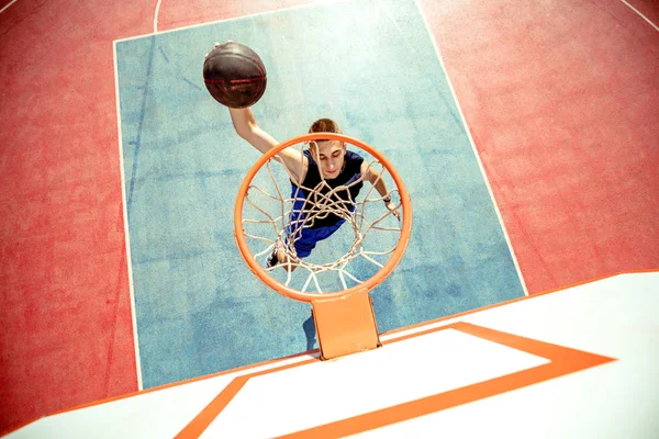 Jongeman die springt en een fantastische slam dunk maakt door streetball te spelen, basketbal. Stedelijk authentiek. — Stockfoto