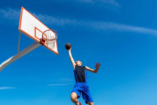 Jovem jogador de basquete de rua fazendo slam dunk — Fotografia de Stock