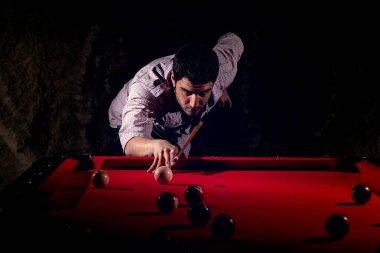 Bir sakallı bir adam büyük bir bilardo oynuyor.