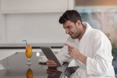 tablet bilgisayar kullanarak evden çalışan bornoz içinde genç serbest meslek