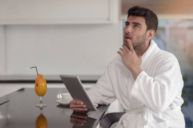 tablet bilgisayar kullanarak evden çalışan bornoz içinde genç serbest meslek