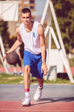 Yakışıklı erkek dışarıda basketbol oynuyor.