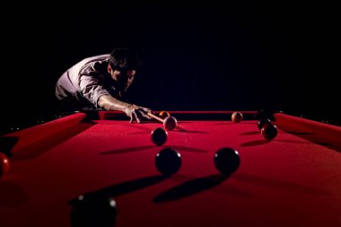 Bir sakallı bir adam büyük bir bilardo oynuyor.