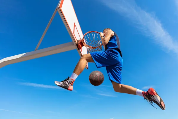 Slam dunk. πλάγια όψη της νεαρός καλαθοσφαιριστής, καθιστώντας το slam dunk — Φωτογραφία Αρχείου