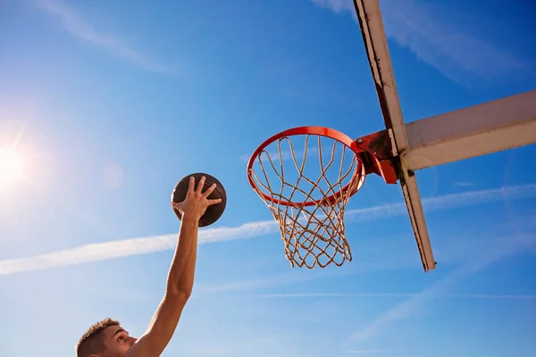 Slam Dunk. Vista lateral del joven jugador de baloncesto haciendo slam dunk — Foto de Stock