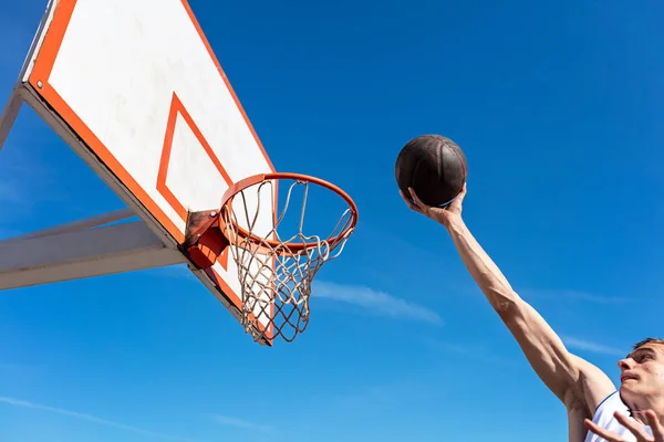 Slam Dunk. Vista lateral del joven jugador de baloncesto haciendo slam dunk — Foto de Stock