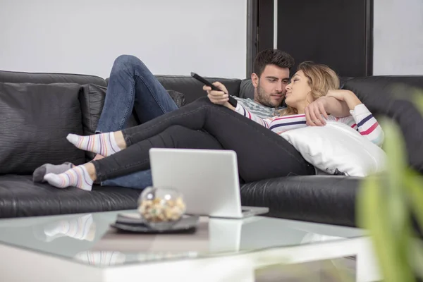 Jovens casais felizes relaxando e assistindo TV em casa . — Fotografia de Stock