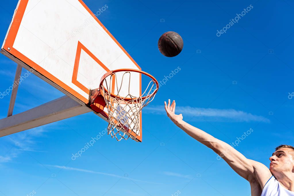 Slam Dunk. Side view of young basketball player making slam dunk
