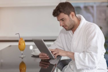 tablet bilgisayar kullanarak evden çalışan bornoz içinde genç serbest meslek