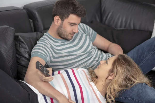 Jovens casais felizes relaxando e assistindo TV em casa . — Fotografia de Stock