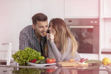 Evdeki mutfakta birlikte yemek pişiren mutlu genç çiftin portresi..