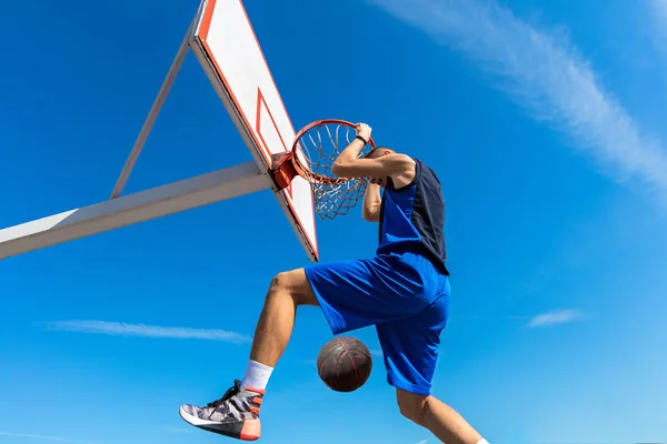 Slam-Dunk. Seitenansicht eines jungen Basketballspielers, der Slam Dunk macht — Stockfoto