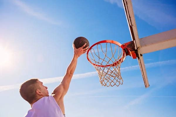Slam Dunk. Vista lateral del joven jugador de baloncesto haciendo slam dunk — Foto de Stock