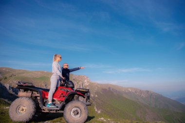 Güzel çift quadbike üzerinde oturan dağ dan gün batımını izlemek