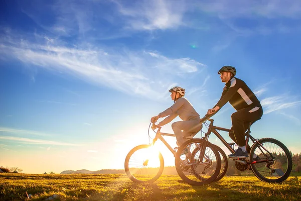 Feliz mountain bike pareja al aire libre divertirse juntos en un verano por la tarde puesta de sol —  Fotos de Stock