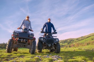 Güzel çift üzerinden atv quadbike üzerinde oturan dağ gün batımını izlemek