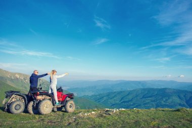 Güzel çift üzerinden atv quadbike üzerinde oturan dağ gün batımını izlemek