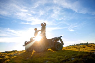 Güzel çift üzerinden atv quadbike üzerinde oturan dağ gün batımını izlemek