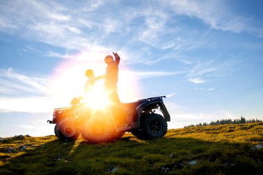 Güzel çift üzerinden atv quadbike üzerinde oturan dağ gün batımını izlemek