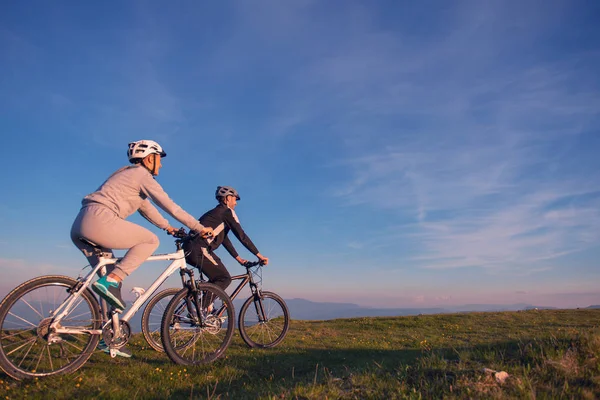 Happy mountainbike couple outdoors have fun together on a summer afternoon sunset — Stock Photo, Image