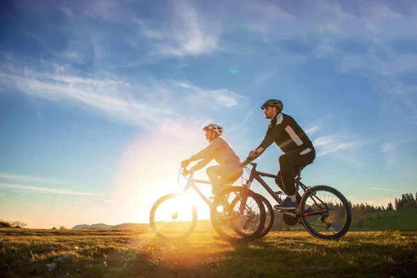 Feliz mountain bike pareja al aire libre divertirse juntos en un verano por la tarde puesta de sol —  Fotos de Stock