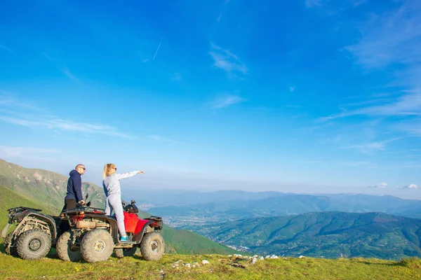 Güzel çift üzerinden atv quadbike üzerinde oturan dağ gün batımını izlemek — Stok fotoğraf